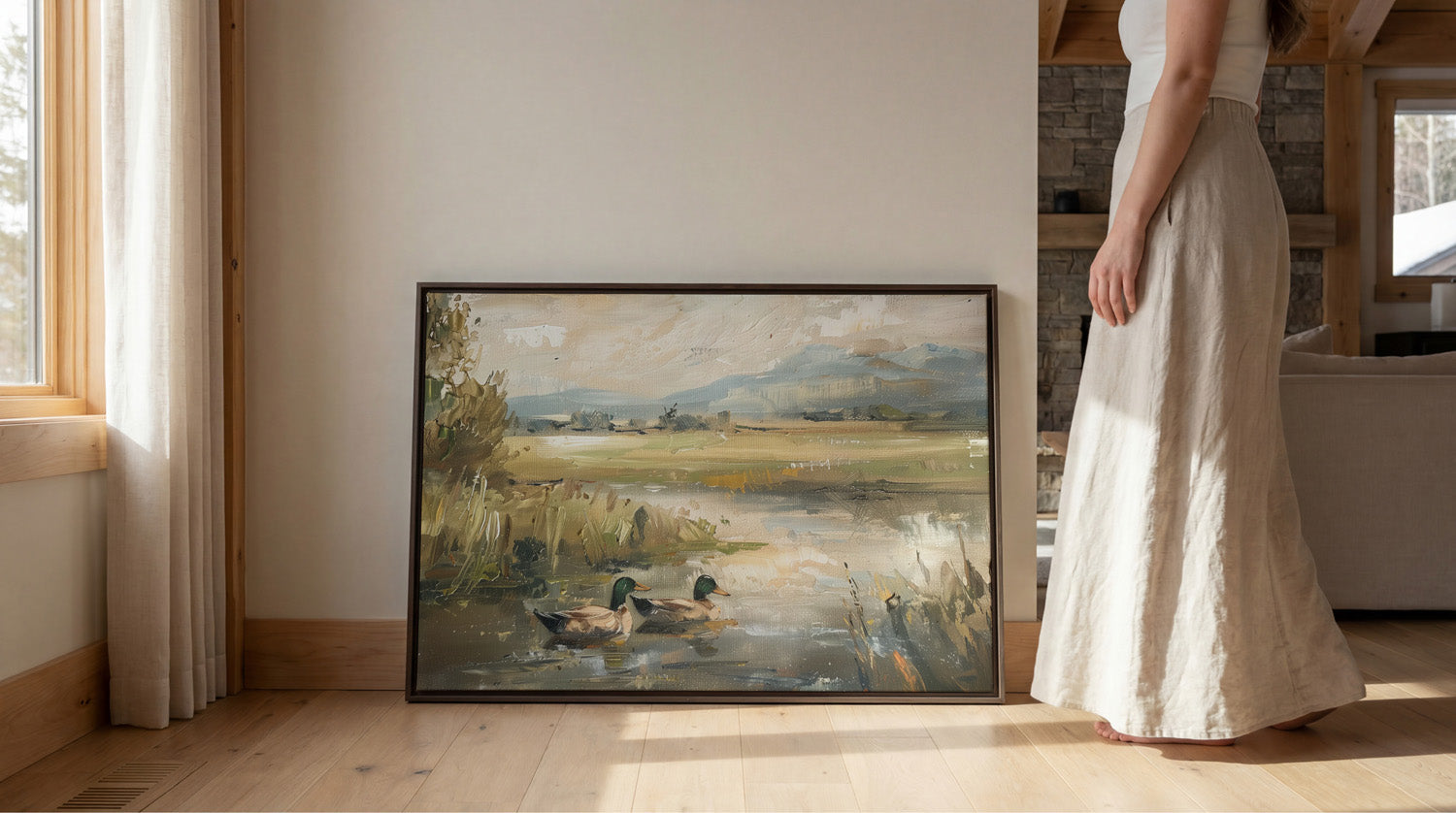 A woman in a long white skirt stands next to a framed painting depicting ducks in a pond, with a window and wooden floor visible in the background.