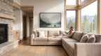 A woman sits on a large beige sectional sofa in a spacious living room, gazing out a large window overlooking a scenic mountain landscape.