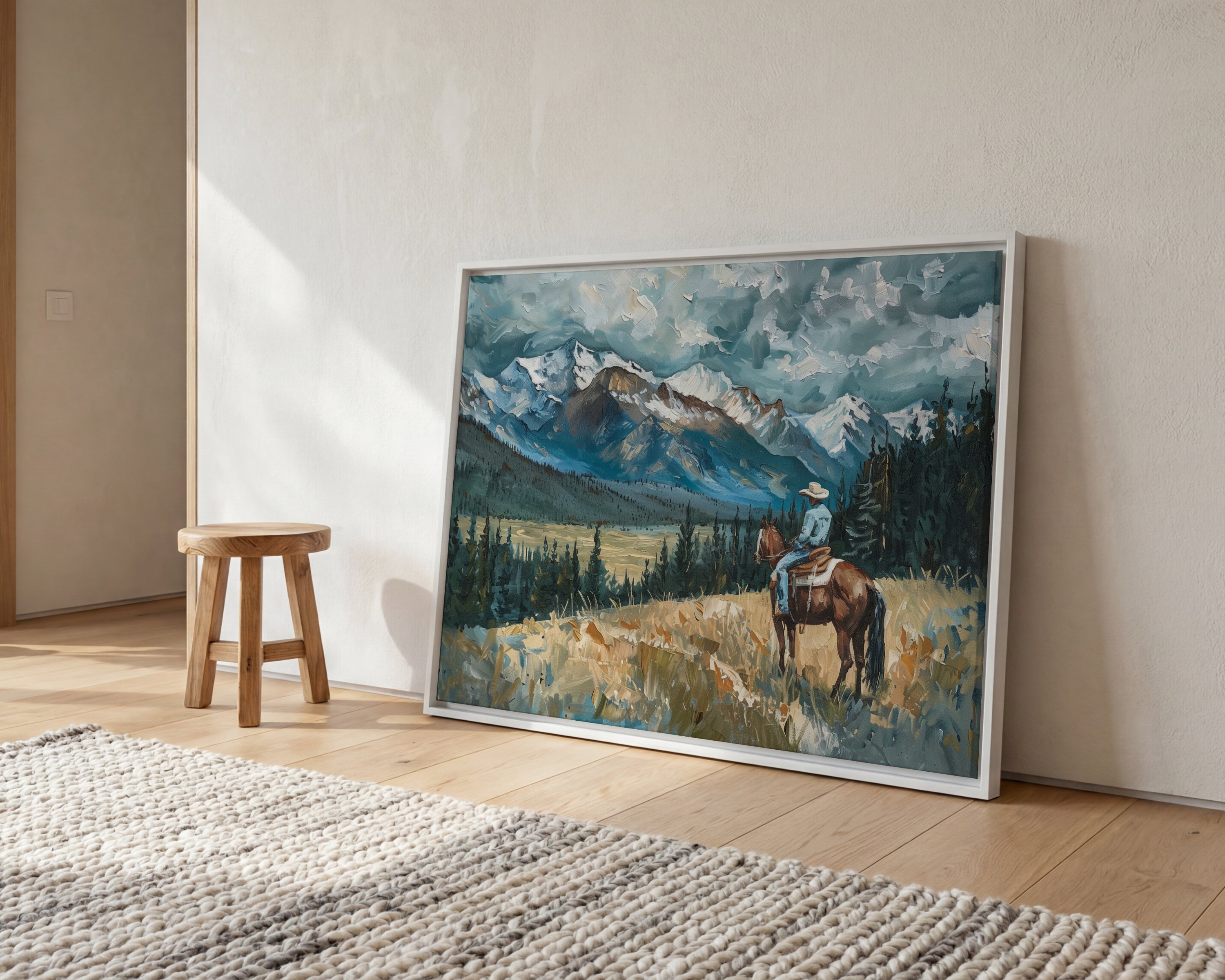 a large painting of a cowboy riding a horse in a mountainous landscape, with a wooden stool and a rug in the foreground.