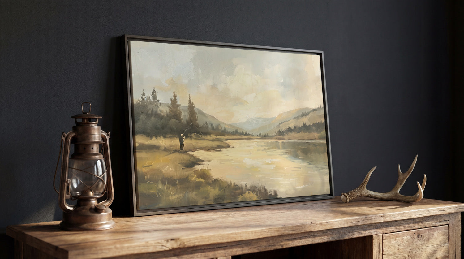 a painting of a serene landscape with a lake, mountains, and trees, displayed on a wooden table. Next to the painting is a lantern and a pair of antlers, creating a rustic and cozy atmosphere.