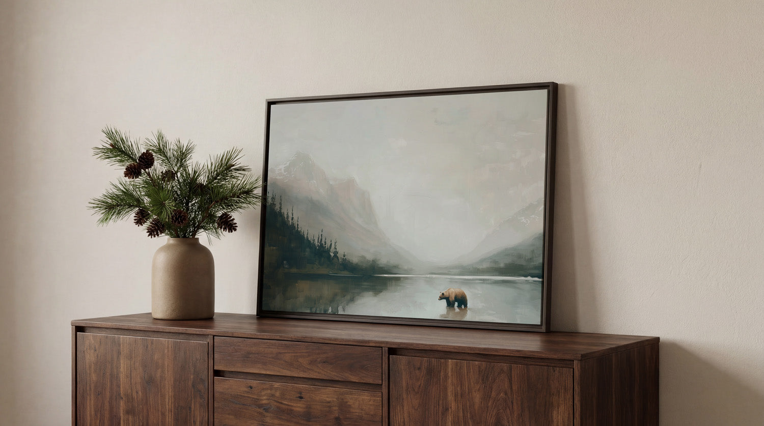 a wooden cabinet with a framed painting of a bear standing in a lake, surrounded by pine trees and mountains.