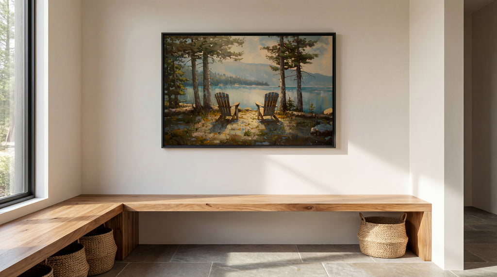 a serene lakeside scene with two wooden chairs positioned on a wooden bench, overlooking a tranquil lake surrounded by trees. Above the bench, a framed painting of a peaceful lakeside landscape is displayed on the wall.