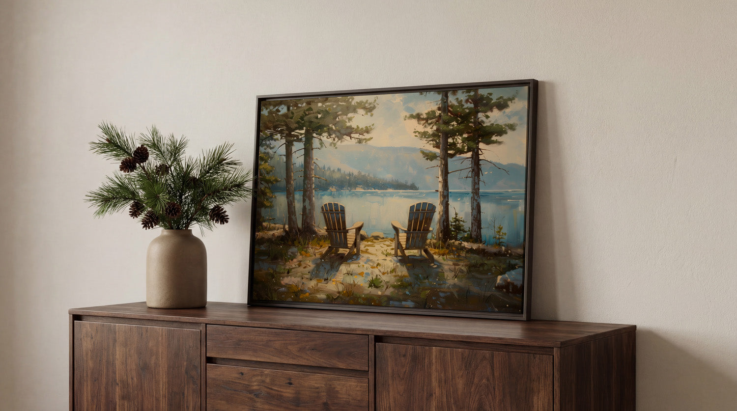 a framed painting of two Adirondack chairs overlooking a lake, surrounded by pine trees and mountains.