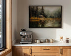 a kitchen counter with a coffee machine, coffee cups, and a framed painting of a cabin in the woods.