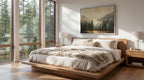 a serene bedroom with a large bed, wooden nightstands, and a painting of a forest landscape on the wall. The room has large windows that provide a view of the surrounding trees, creating a peaceful and natural atmosphere.