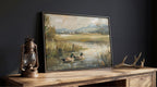 a painting of ducks swimming in a pond, displayed on a wooden table next to a lantern.